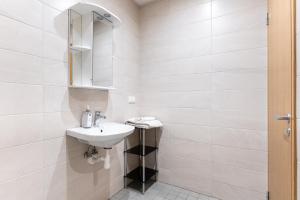 La salle de bains blanche est pourvue d'un lavabo et d'un miroir. dans l'établissement LKS Apartment 3, à Tallinn