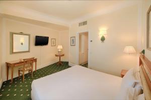 カルタジローネにあるNH Caltagirone Villa San Mauroのベッドとデスクが備わるホテルルームです。