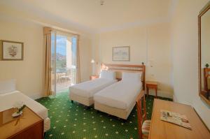 una camera d'albergo con due letti e un tavolo di NH Caltagirone Villa San Mauro a Caltagirone