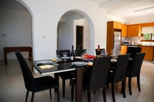 een eetkamer met een tafel en zwarte stoelen bij VILLA LAMBRIANA in Peyia