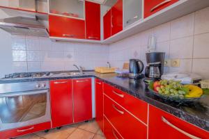 a kitchen with red cabinets and a bowl of fruit on the counter at Cozy apartments with sea view in Novi Vinodolski