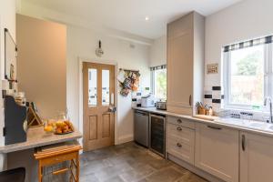 a kitchen with white cabinets and a sink and a window at Finest Retreats - Hillview House in Minehead