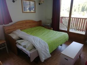 ein Schlafzimmer mit einem grünen Bett und einem Balkon in der Unterkunft Espace et confort dans station familiale à 1800 m in Puy-Saint-Vincent