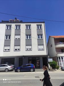 a woman walking down a street in front of a building at Apartman Đerić in Nevesinje