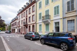 zwei Autos, die an einer Straße mit Gebäuden geparkt sind in der Unterkunft Travel Homes - Le Carls 1 spacieux, moderne, équipé in Mulhouse