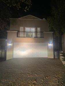 uma casa com uma porta de garagem branca à noite em 6th on Brooke av em Joanesburgo