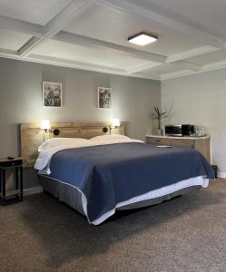 ein großes Bett in einem Schlafzimmer mit zwei Tischen und zwei Lampen in der Unterkunft BlueGem Motel in High Springs