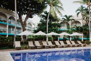 a pool at the resort with lounge chairs and umbrellas at Hotel Suites Villasol in Puerto Escondido