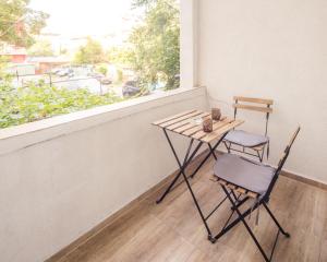 einen Tisch und zwei Stühle auf einem Balkon mit Fenster in der Unterkunft Aleks Sunrise -Top Center ,Sea Garden in Burgas City