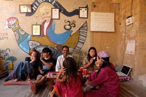 un grupo de personas sentadas frente a una pared en Hotel Mirage, en Jaisalmer