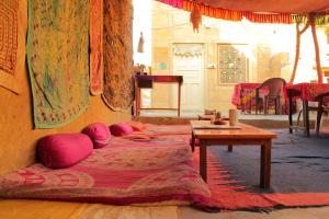 ジャイサルメールにあるHotel Mirageのピンクの枕とテーブル付きのベッド2台が備わる客室です。