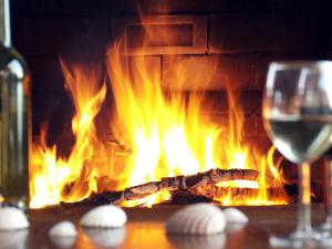 a glass of wine next to a fireplace with flames at Lar Atlantis in Basoñas