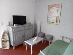 a room with a tv and a table and a chair at A deux pas d'la mer in Grandcamp-Maisy