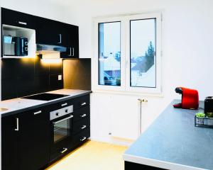 eine Küche mit schwarzen Schränken und einem großen Fenster in der Unterkunft Bella Luna II - Elégant appartement centre ville - Parking gratuit - Wifi ultra rapide-Appareil Massage-Netflix-Jeu société in Troyes