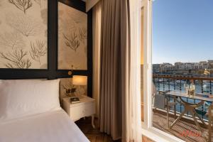 a bedroom with a bed and a balcony with a table at Eldoris Boutique Living in Marsaskala