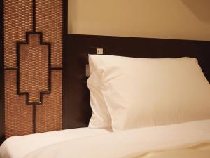 a bed with a white pillow and a black headboard at Vessel Inn Hakata Nakasu in Fukuoka