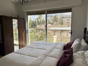 un grande letto in una stanza con una grande finestra di Ronza Elegant Apartment ad Amman