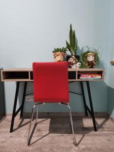a red chair sitting in front of a desk at Apartament Madlen Art in Olecko