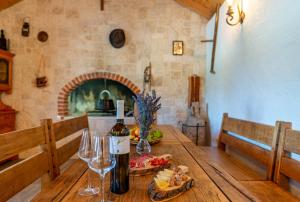 einen Holztisch mit einer Flasche Wein und Weingläsern in der Unterkunft Old Olive in Murvica