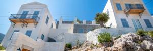 a white building with a rock in front of it at The Anchor House in Symi