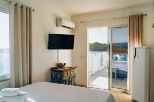 a bedroom with a bed and a sliding glass door at Casa Grega in Arraial do Cabo