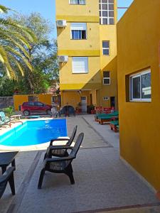 a swimming pool with two chairs and a building at El Descanso Hotel in Termas de Río Hondo