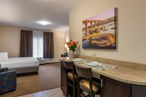 a hotel room with a king bed and a kitchen with a bar at Stay-Over Suites - Fort Gregg-Adams Area in Hopewell