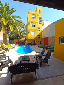 eine Terrasse mit Stühlen, einem Pool und einem Gebäude in der Unterkunft El Descanso Hotel in Termas de Río Hondo