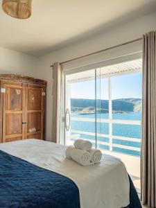 1 dormitorio con cama y ventana grande en Casa Santorini Terrace, en Arraial do Cabo