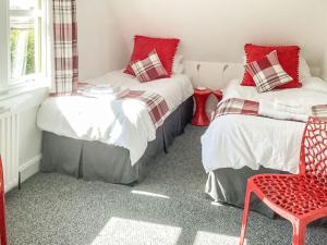 a bedroom with two beds and a red chair at Shoreline in Connel