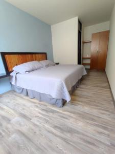 1 dormitorio con 1 cama grande y suelo de madera en El salto de Camela Hostal en Uruapan del Progreso