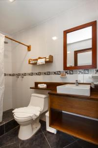 a bathroom with a toilet and a sink and a mirror at Casita de la Playa in Puerto Villamil