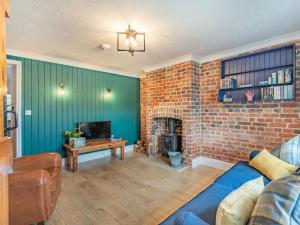 a living room with a blue couch and a brick wall at Keepers Cottage in Grimston