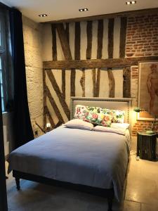 een slaapkamer met een bed en een bakstenen muur bij Atelier dans un hotel particulier in Pont-Audemer