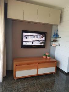 een kamer met een televisie aan een muur met een bank bij Condomínio Arituba Tropical in Nísia Floresta