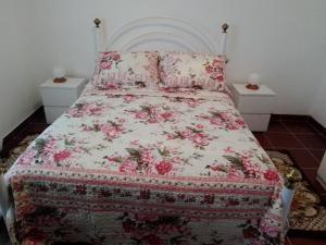 een slaapkamer met een bed met een bloemenbed en kussens bij CASA DA ALDEIA - Ponte de Sor (Alentejo) in Ponte de Sor