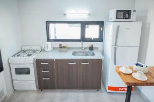 a kitchen with a white refrigerator and a sink at Cabañas El Aby in El Bolsón +2 photos