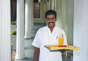 a man holding a tray with a drink on it at Hotel Sunflower in Kataragama