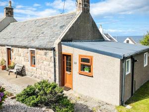 a stone cottage with a blue roof and a patio at Portknockie Escape in Portknockie