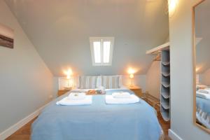 a bedroom with a blue bed with towels on it at 6 Coastguard Cottages, Aldeburgh in Aldeburgh