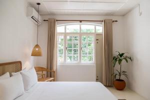 1 dormitorio con cama blanca y ventana en Srilax en Colombo