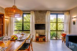 a living room with a dining room table and some windows at Chic Suites in the Heart of Tulum by Stella Rentals in Tulum