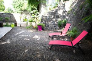 twee rode stoelen naast een stenen muur bij Le Bambou T3 Centre ville Sainte Clotilde Rez de jardin in Bois de Nèfles