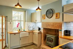 a kitchen with white cabinets and a fireplace at Finest Retreats - Peak View in Two Dales