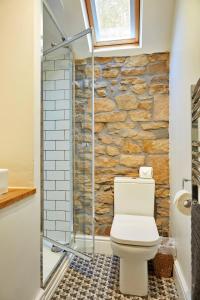 a bathroom with a toilet and a stone wall at Finest Retreats - Peak View in Two Dales