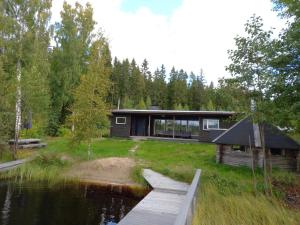 a house on the water with a wooden dock at Private Lakeside Holiday Property in Nature in Kankaanpää