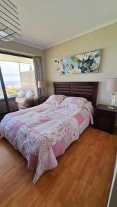 1 dormitorio con 1 cama con colcha rosa en Departamento en Viña del Mar Cochoa-Reñaca, en Viña del Mar
