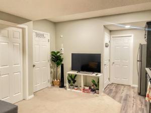 a living room with a tv and two white doors at Cozy Newly Built and Cheerful 1-Bedroom Suite in Calgary