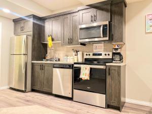 a kitchen with stainless steel appliances and wooden cabinets at Cozy Newly Built and Cheerful 1-Bedroom Suite in Calgary