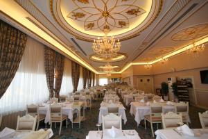 a banquet hall with white tables and chairs and chandeliers at Demir Hotel in Diyarbakır